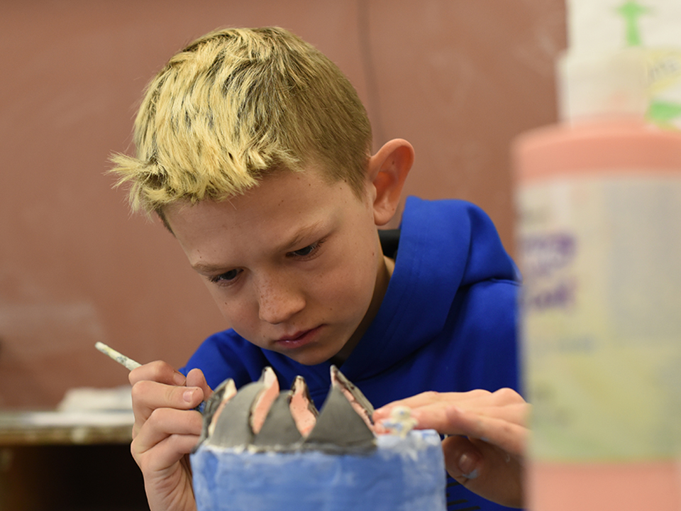 Student painting clay sculpture