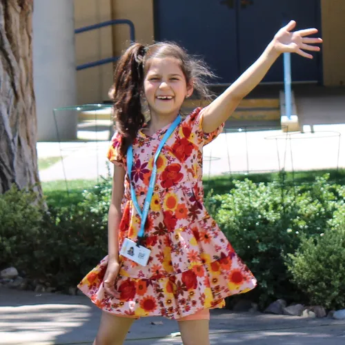 camper smiling and waving at the camera outside