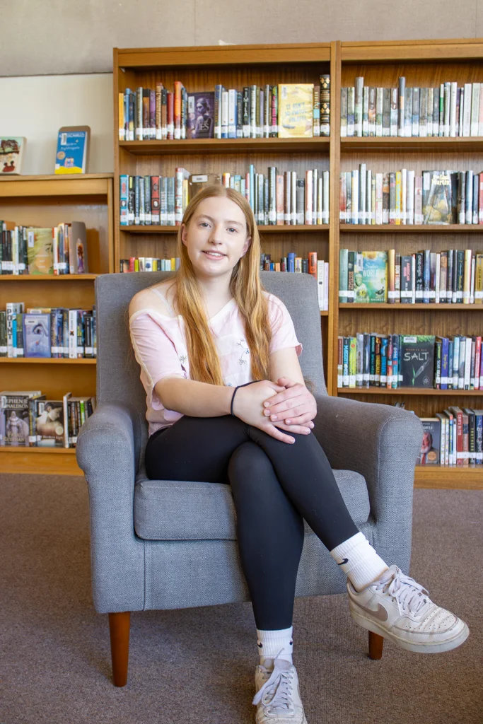 student Amelia sitting in a chair in the library