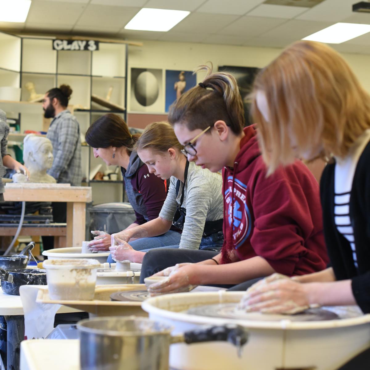 Line of students at pottery wheels